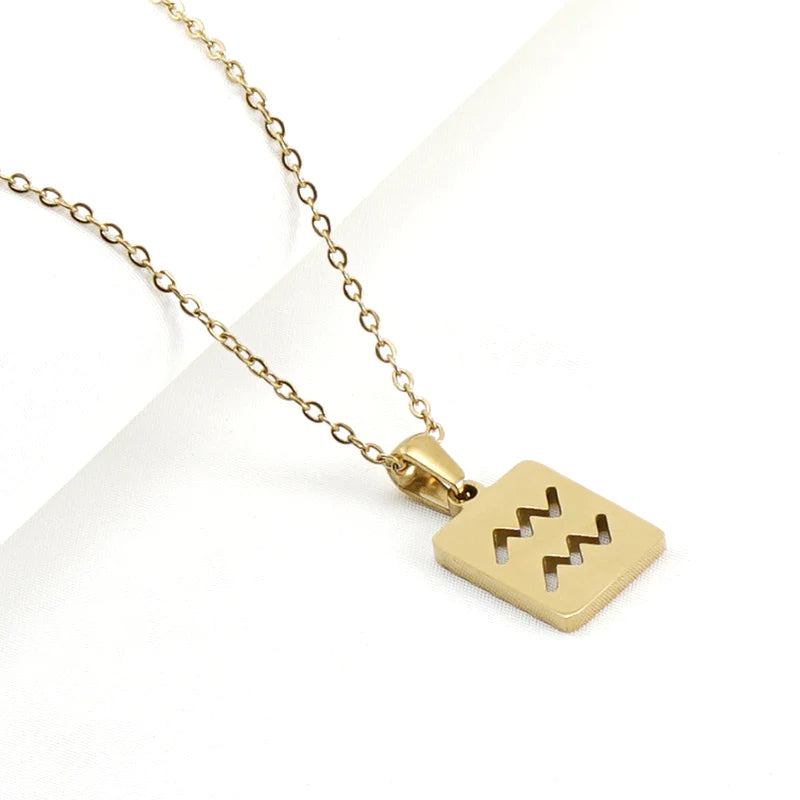 A gold necklace with a dainty chain and rectangular pendant in the  Aquarius style.