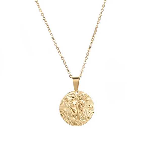 A gold necklace with a dainty chain. The necklace has a coin pendant displaying the astrological sign Gemini of the zodiac.