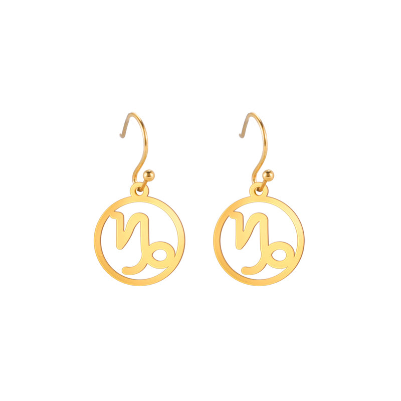 Gold earrings with the astrological symbol for Capricorn. The zodiac earrings are suspended in the air with a white background. 