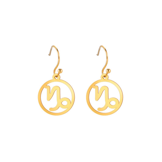 Gold earrings with the astrological symbol for Capricorn. The zodiac earrings are suspended in the air with a white background. 