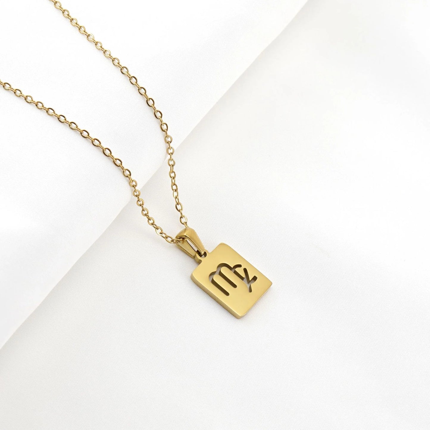 A gold necklace with a dainty chain and rectangular pendant in the Virgo style. 